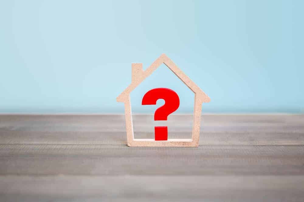 Question mark with house on wood table, home selling questions concept