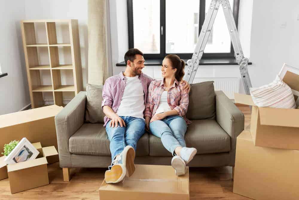 young couple on a sofa surrounded by moving boxes