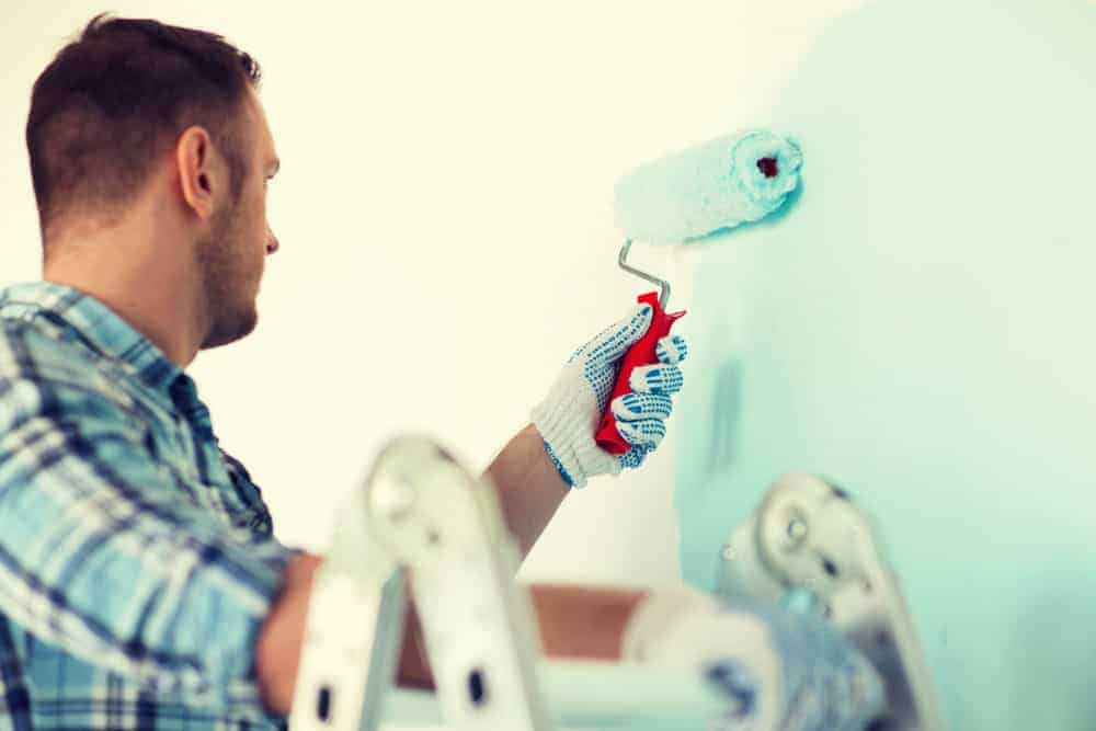 a man painting an interior home wall