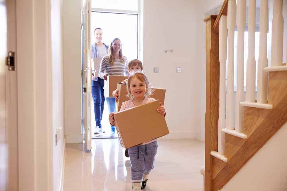Family Moving into a new home carrying moving boxes