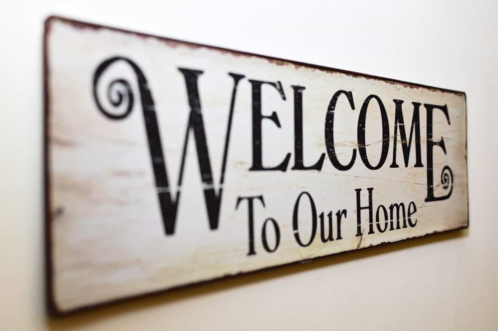 Welcome to our home sign hanging on a wall