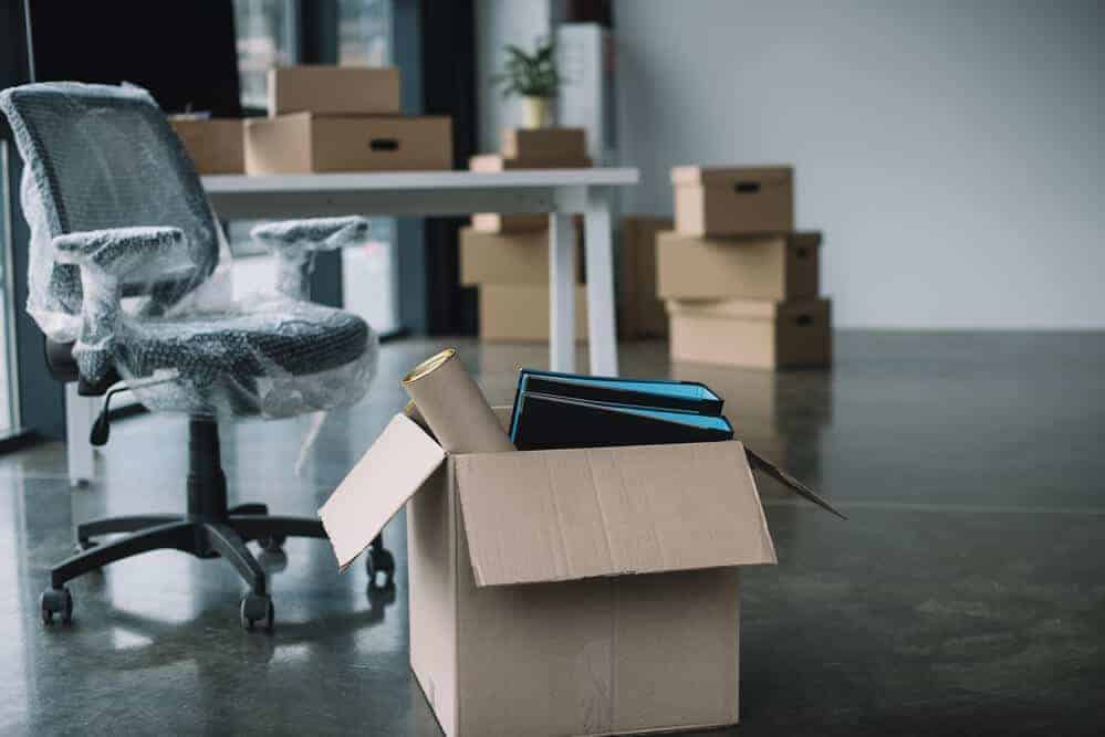 packed up office with moving boxes and a wrapped desk chair